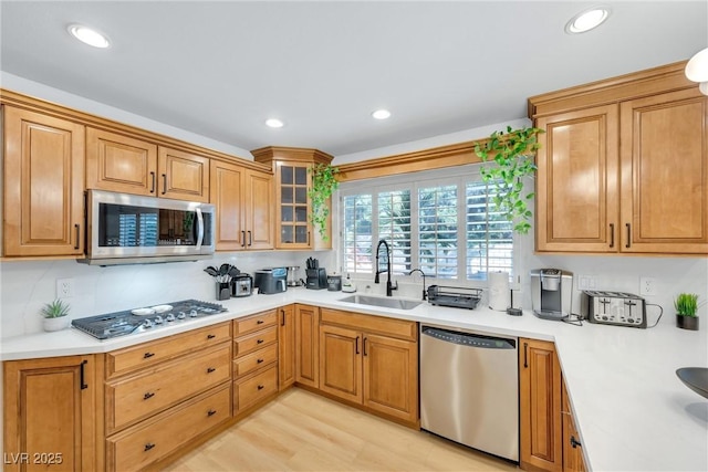 kitchen with light hardwood / wood-style flooring, sink, stainless steel appliances, and backsplash