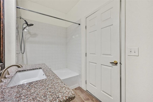 bathroom featuring hardwood / wood-style flooring, tiled shower / bath, and vanity