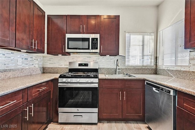 kitchen featuring sink, decorative backsplash, stainless steel appliances, and light wood-type flooring