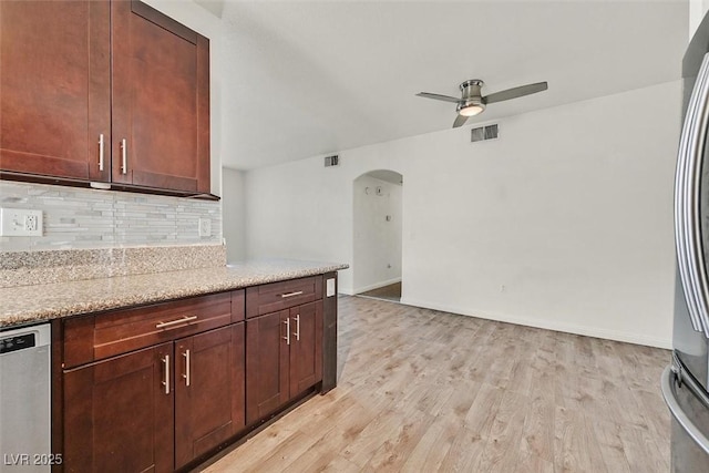 kitchen featuring ceiling fan, tasteful backsplash, light stone counters, light hardwood / wood-style floors, and stainless steel dishwasher