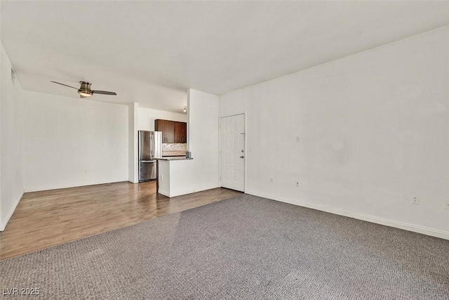 unfurnished living room featuring ceiling fan and dark colored carpet