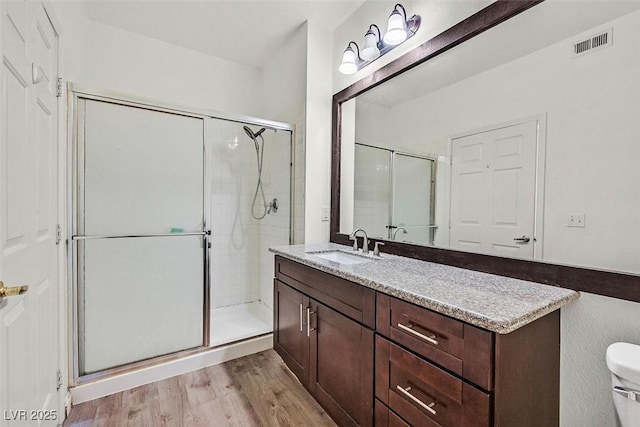 bathroom featuring walk in shower, wood-type flooring, toilet, and vanity