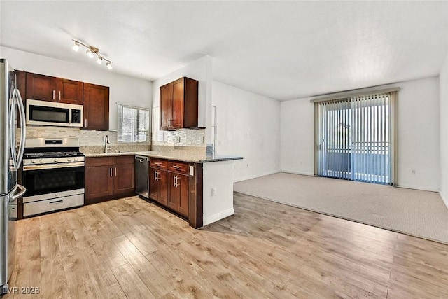 kitchen featuring sink, light stone counters, tasteful backsplash, appliances with stainless steel finishes, and light hardwood / wood-style floors