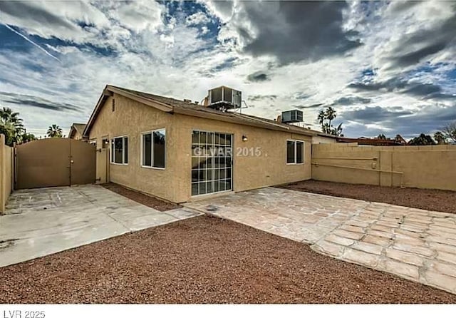 rear view of property with cooling unit and a patio area