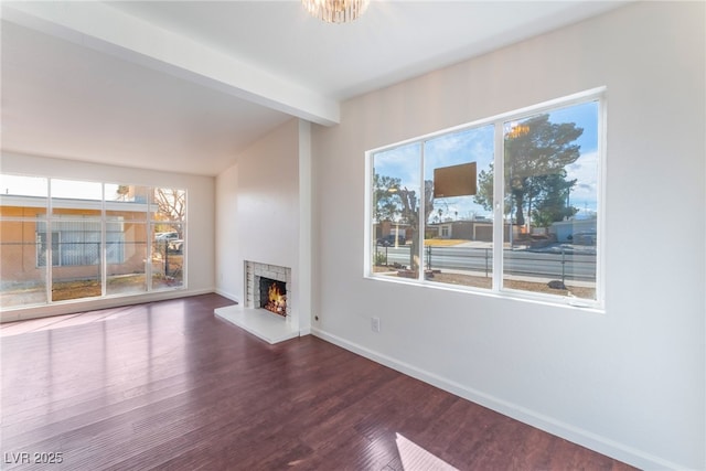 unfurnished living room with beamed ceiling, dark wood-type flooring, and a wealth of natural light