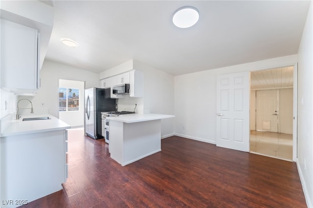 kitchen with sink, white cabinetry, stainless steel appliances, dark hardwood / wood-style flooring, and kitchen peninsula