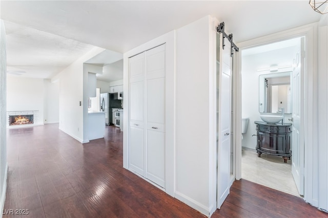 corridor with sink, dark hardwood / wood-style floors, and a barn door