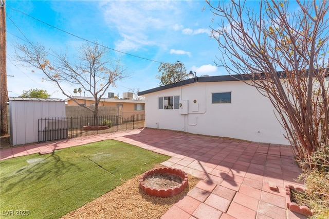 rear view of property featuring a shed, a patio, and a lawn