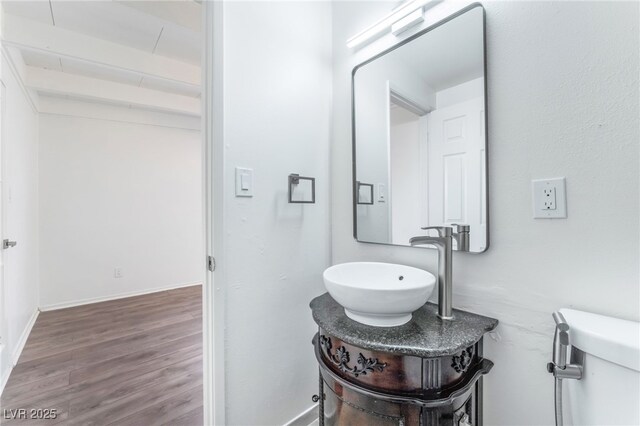 bathroom featuring beamed ceiling, vanity, toilet, and hardwood / wood-style floors