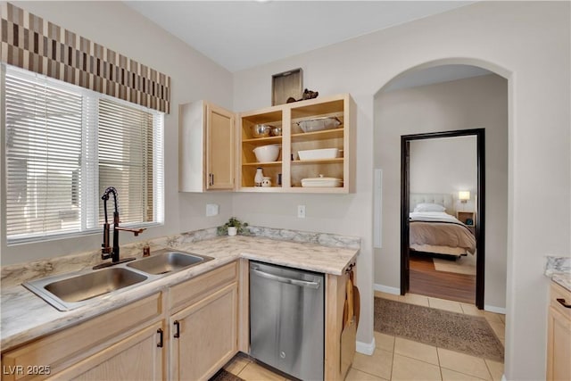 kitchen with light tile patterned flooring, sink, stainless steel dishwasher, and light brown cabinets