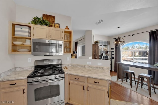 kitchen with hanging light fixtures, a notable chandelier, kitchen peninsula, stainless steel appliances, and light brown cabinets