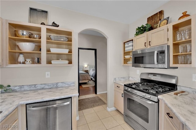 kitchen with light stone counters, appliances with stainless steel finishes, and light tile patterned flooring