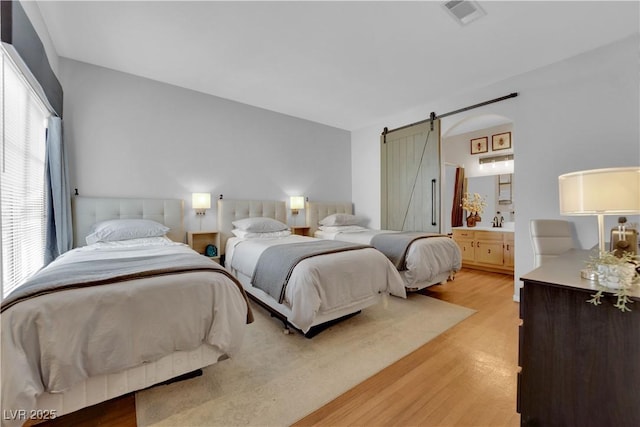 bedroom with a barn door and light wood-type flooring