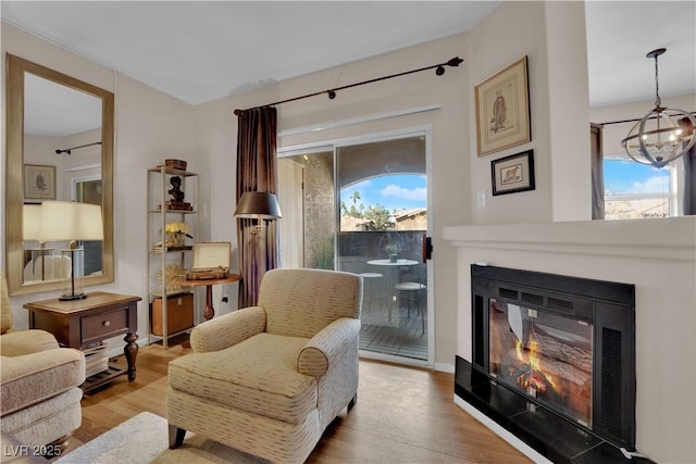 living area with a chandelier, light hardwood / wood-style floors, and a wealth of natural light