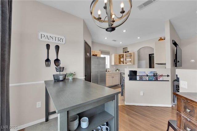 kitchen with pendant lighting, a notable chandelier, high end refrigerator, and light hardwood / wood-style floors