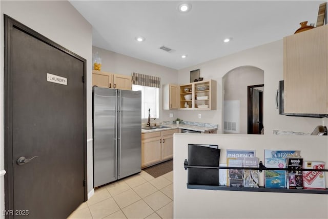 kitchen featuring high end refrigerator, sink, light brown cabinets, and light tile patterned floors