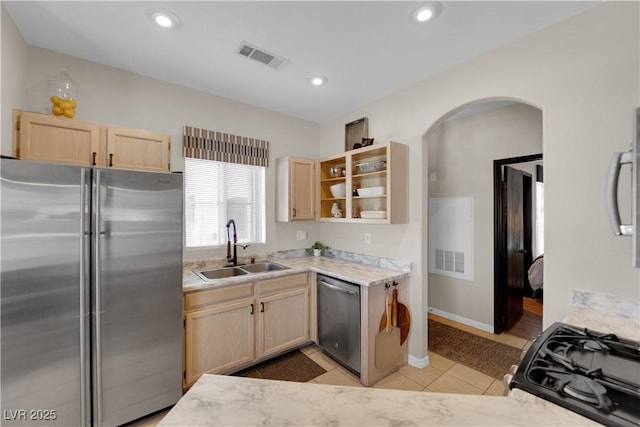 kitchen with stainless steel appliances, sink, light tile patterned floors, and light brown cabinetry