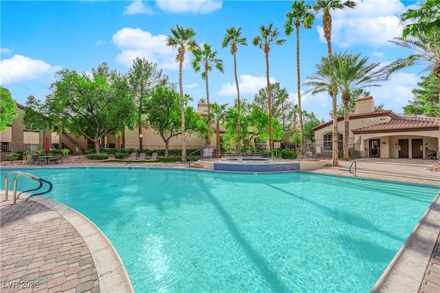 view of swimming pool featuring a hot tub and a patio area