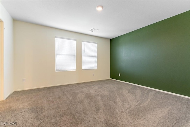 spare room with carpet, visible vents, and baseboards