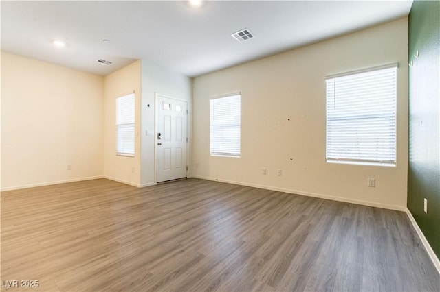 unfurnished room featuring baseboards, visible vents, and wood finished floors