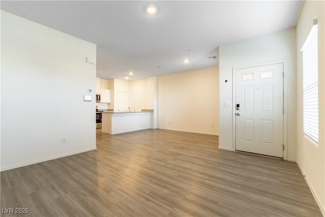 unfurnished living room with baseboards, wood finished floors, and recessed lighting