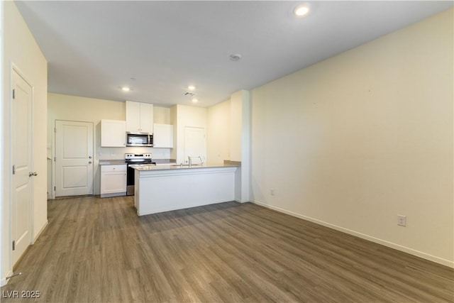 kitchen featuring dark wood-style flooring, stainless steel appliances, open floor plan, white cabinets, and a peninsula