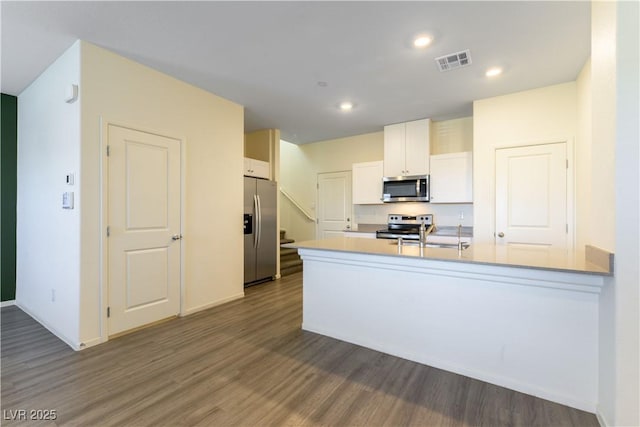 kitchen with visible vents, wood finished floors, stainless steel appliances, light countertops, and white cabinetry