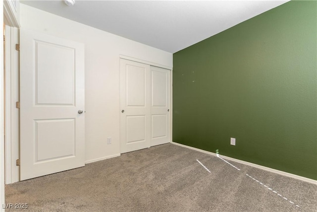 unfurnished bedroom with a closet, baseboards, and carpet flooring