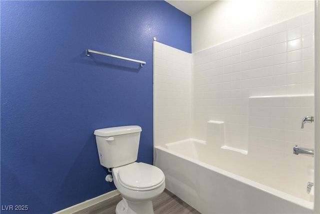 bathroom with toilet, baseboards, wood finished floors, and shower / bathing tub combination