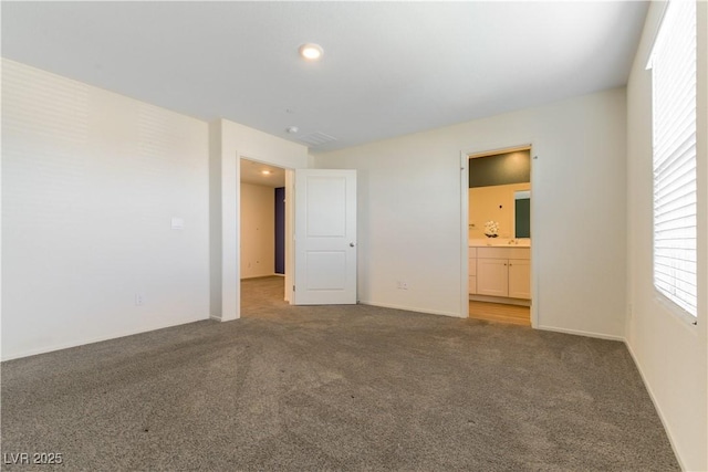 unfurnished bedroom with ensuite bathroom, carpet floors, and baseboards