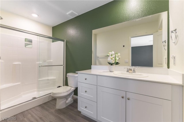 bathroom with toilet, a stall shower, wood finished floors, and vanity