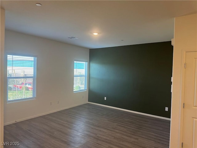 empty room with recessed lighting, dark wood-style flooring, visible vents, and baseboards