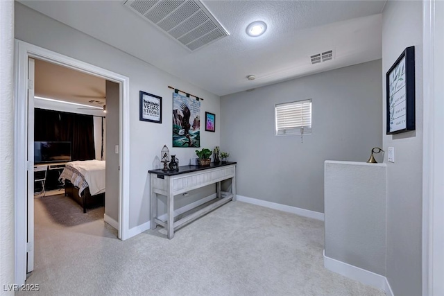 hallway featuring light carpet and a textured ceiling