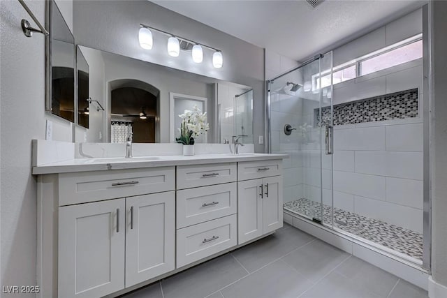 bathroom with walk in shower, vanity, and tile patterned flooring