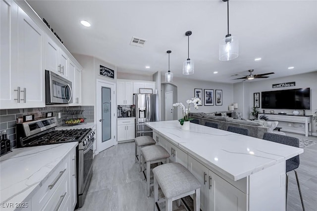 kitchen with pendant lighting, white cabinetry, a breakfast bar area, stainless steel appliances, and light stone countertops