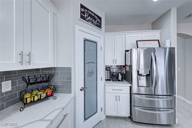 kitchen with white cabinetry, light stone countertops, and stainless steel fridge with ice dispenser