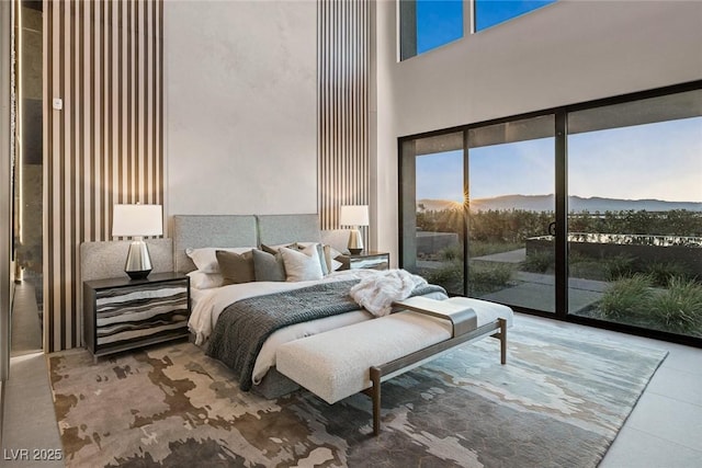 bedroom with access to exterior, a mountain view, and a high ceiling