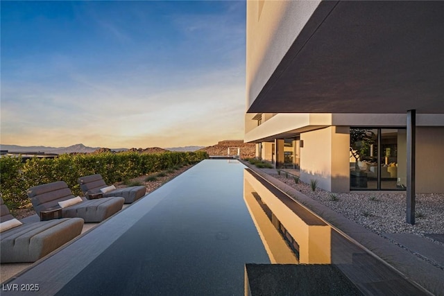 pool at dusk featuring a mountain view