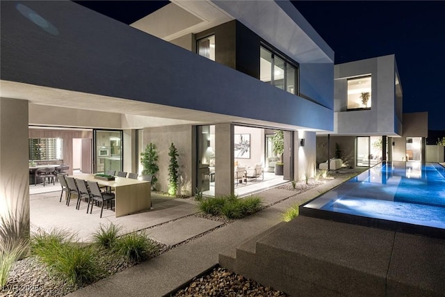 back house at twilight featuring a patio