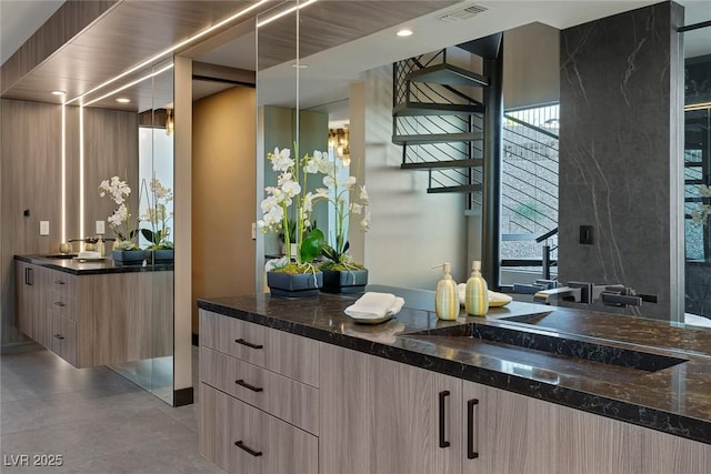 bar with dark stone countertops, sink, and light brown cabinets