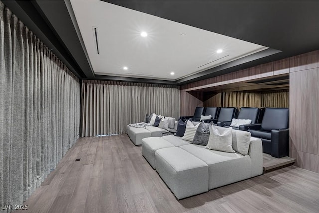 home theater room with a raised ceiling and light wood-type flooring