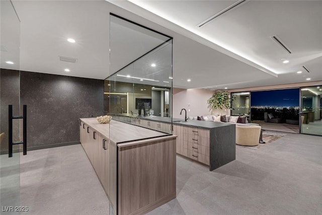 kitchen featuring sink, kitchen peninsula, light brown cabinets, and a spacious island