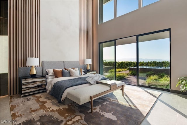 bedroom featuring multiple windows, access to exterior, and a towering ceiling