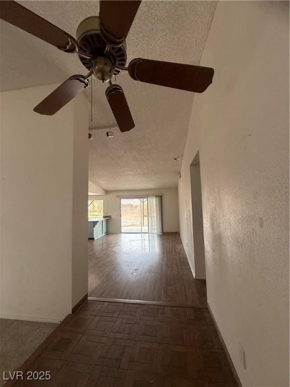 corridor with parquet flooring, baseboards, and a textured ceiling