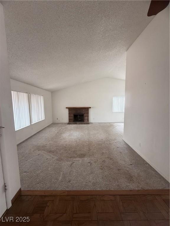 unfurnished living room featuring vaulted ceiling, a fireplace, and a textured ceiling