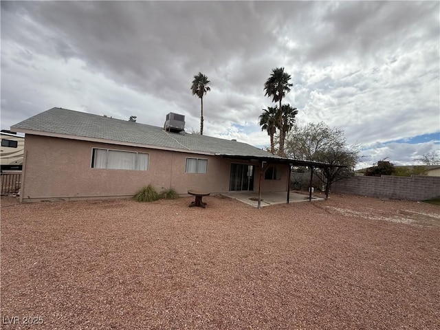 rear view of property featuring stucco siding, cooling unit, a patio, and fence