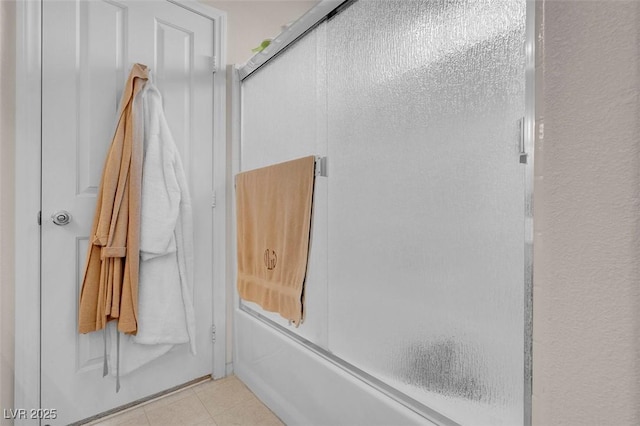 bathroom featuring combined bath / shower with glass door and tile patterned flooring