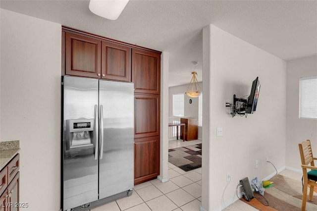 kitchen featuring stainless steel fridge, decorative light fixtures, light tile patterned floors, and a wealth of natural light