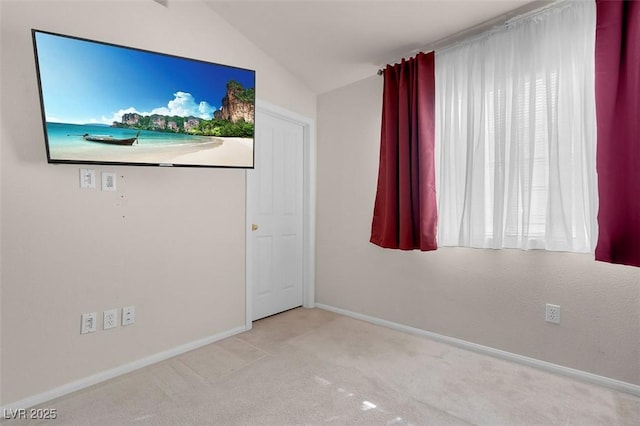 empty room featuring vaulted ceiling, a healthy amount of sunlight, and light carpet