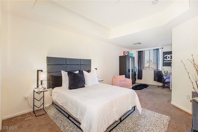 bedroom with a raised ceiling and carpet flooring